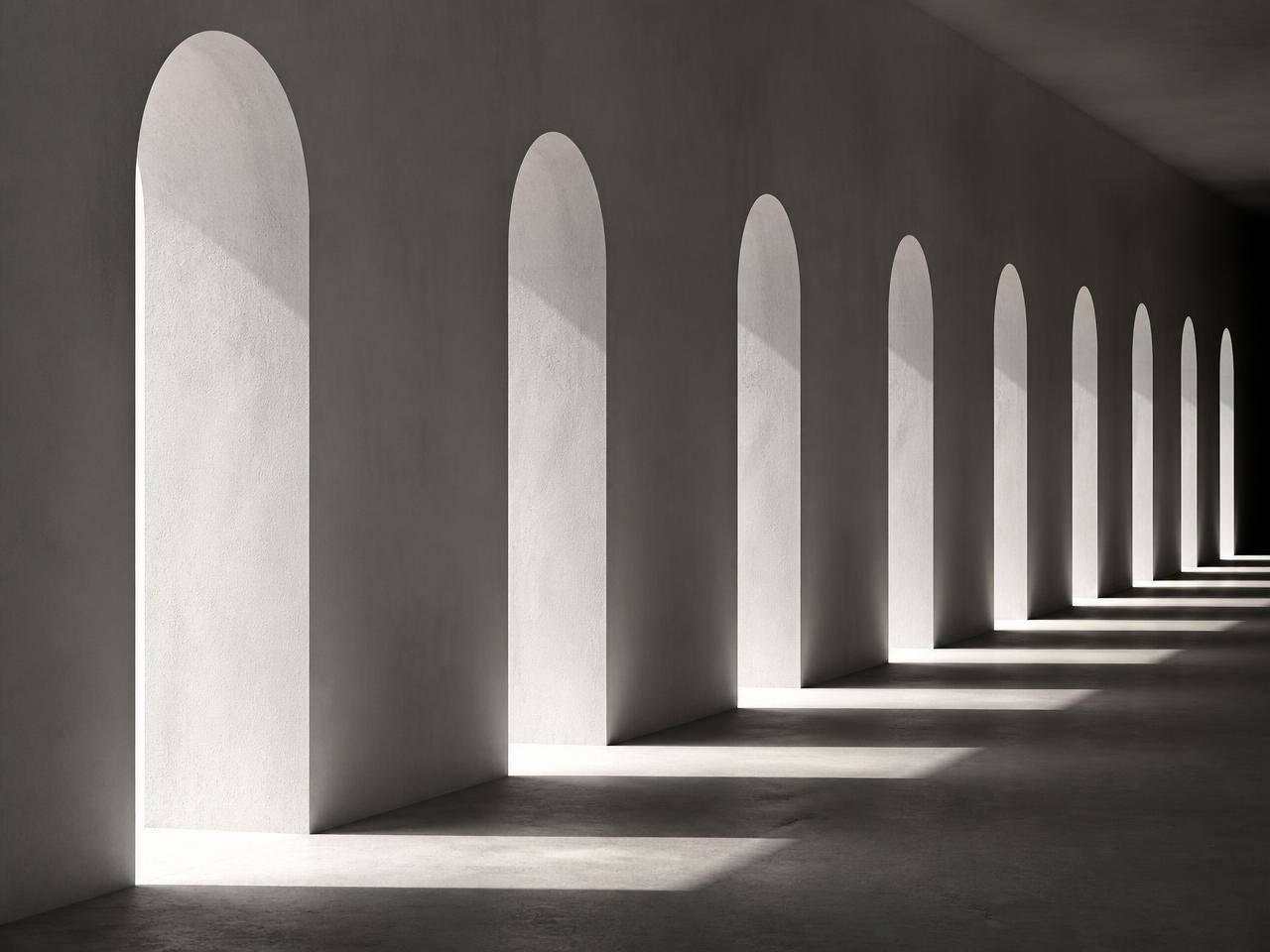 Row of tall narrow arched openings in a pale plaster wall, light falling to the floor