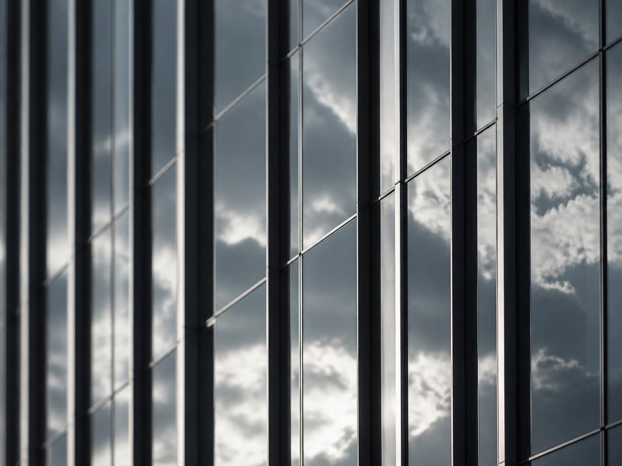 Close crop of a glass curtain wall, vertical mullions and reflected sky